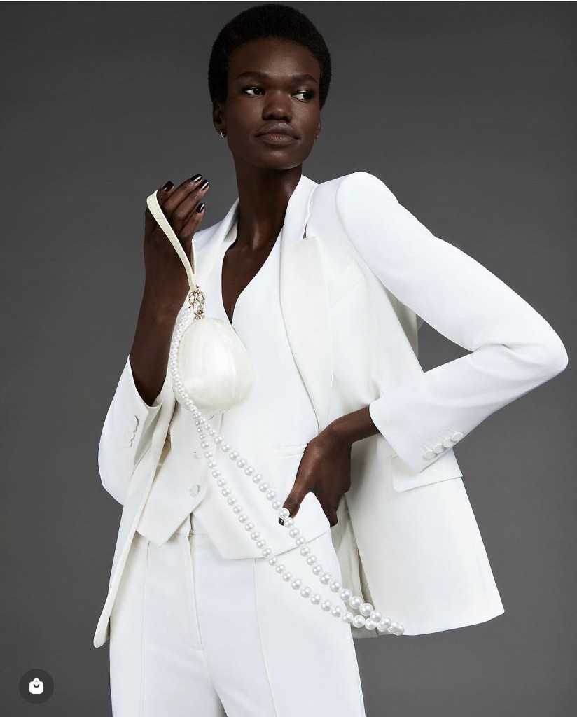 Alek Malek in a tailored white suit with pearl accessories, editorial portrait
